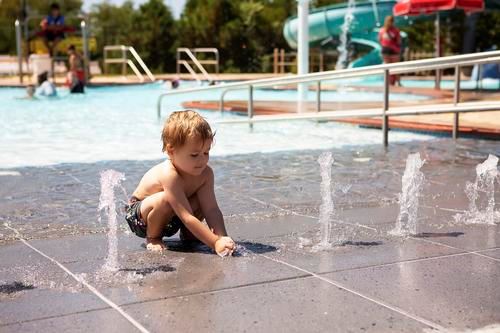 Boy playing in water spray at Cove Point Pool