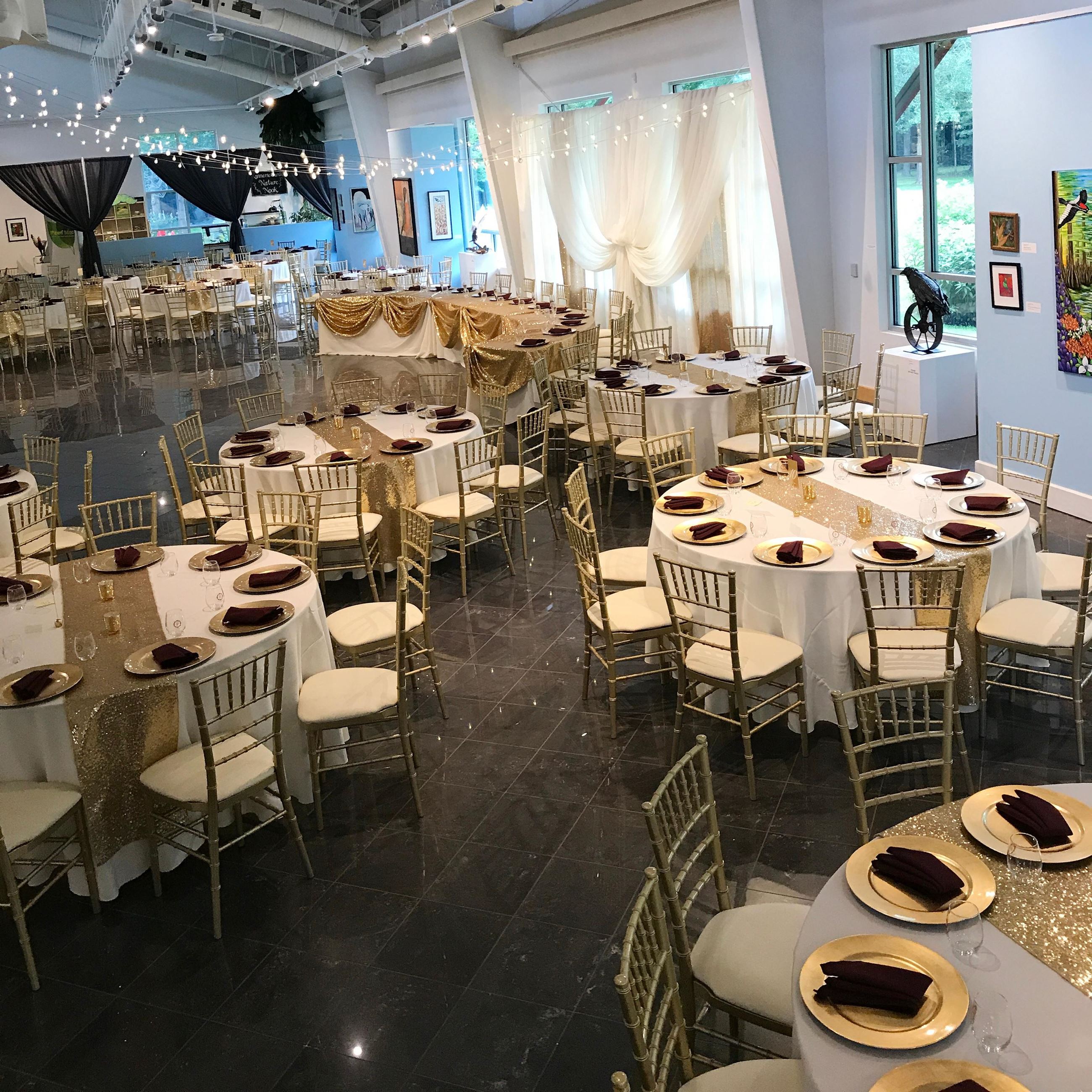 Dining area for a wedding with gold and maroon place settings