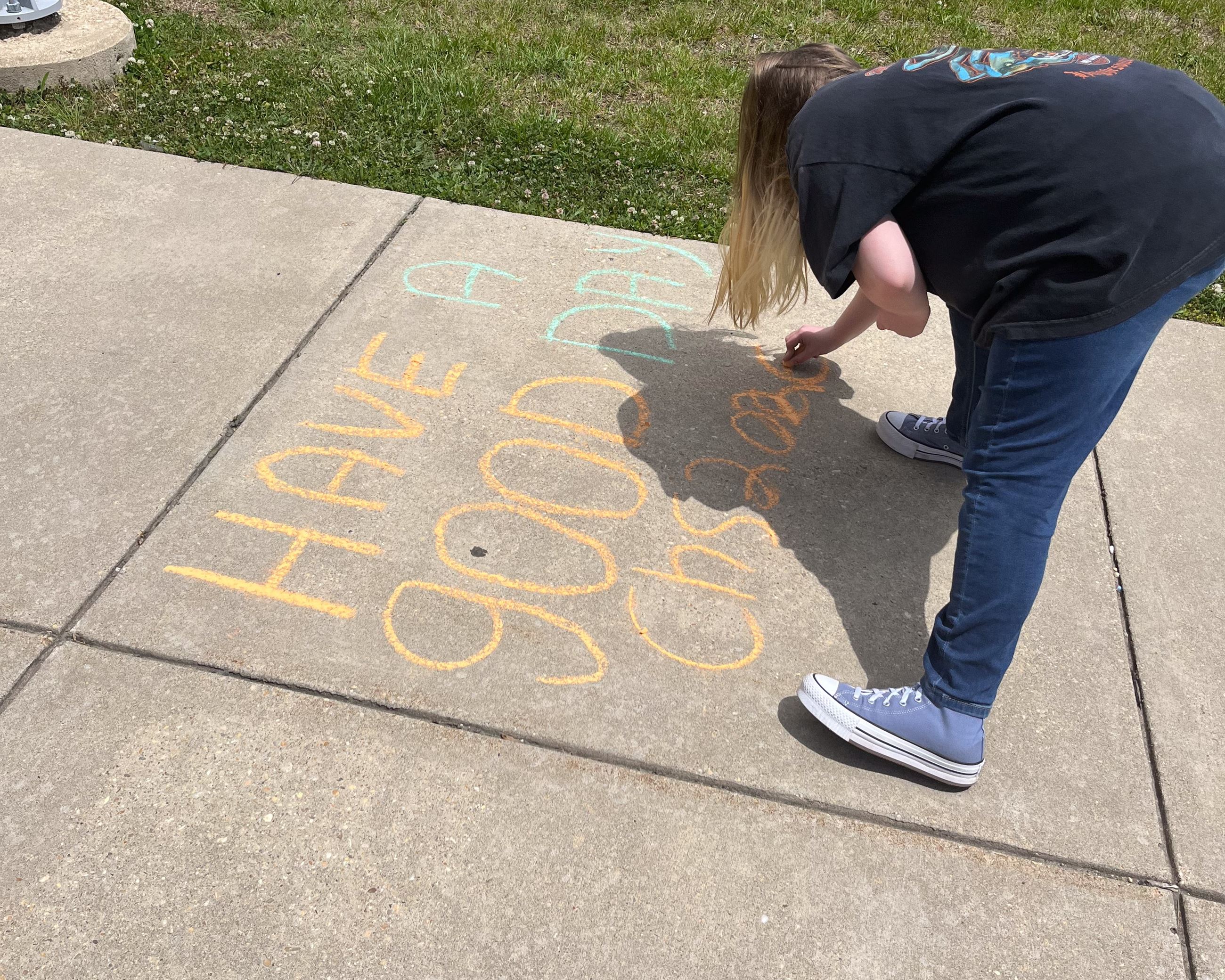 5 students in front of Calvert High School drawing with chalk.