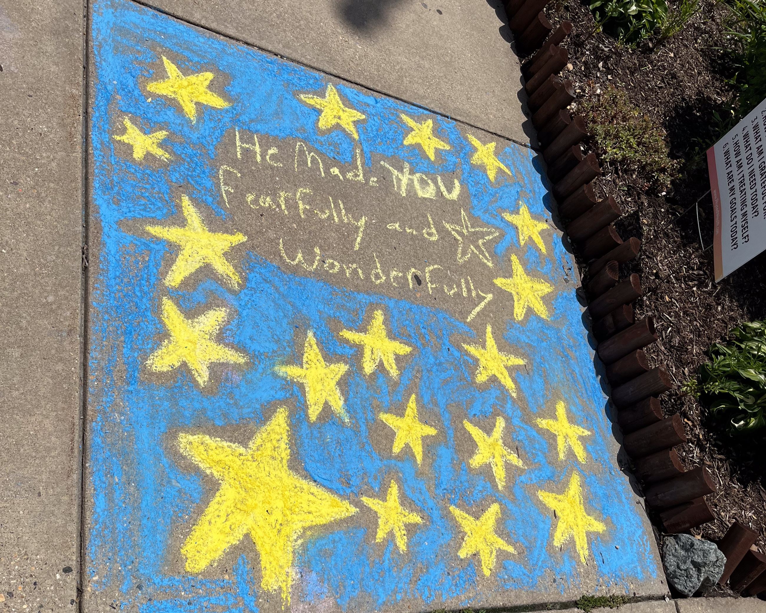 Multicolored swirl sidewalk chalk art in front of a flagpole.