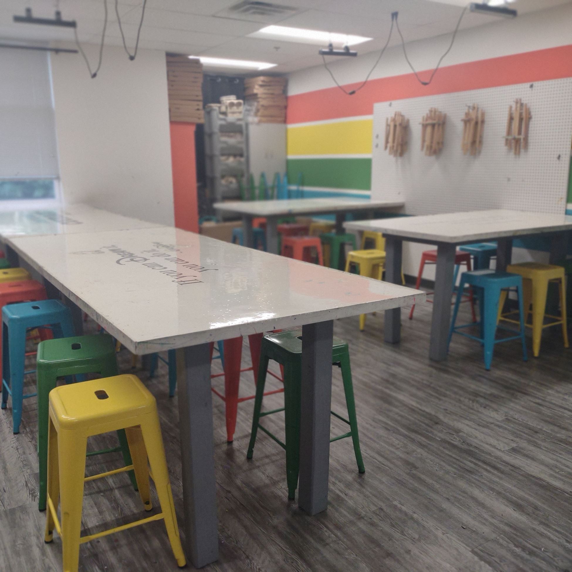 art studio with white tables surrounded by colored stools