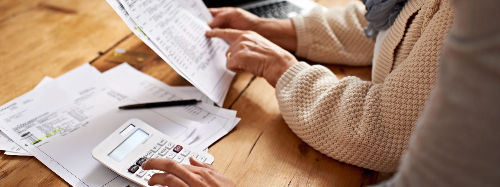 womans hands on a calculator and pointing to a bill