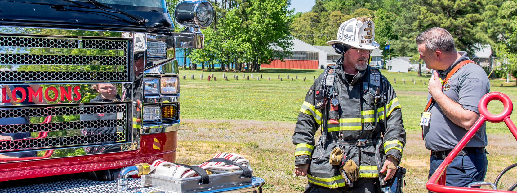 Two men in uniform standing near a firetruck